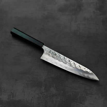 A gyuto with a textured blade and dark handle.