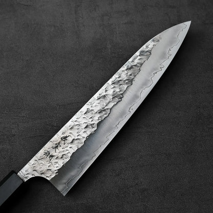 A gyuto with a hammered blade, blade facing left, positioned horizontally for clear visual display.