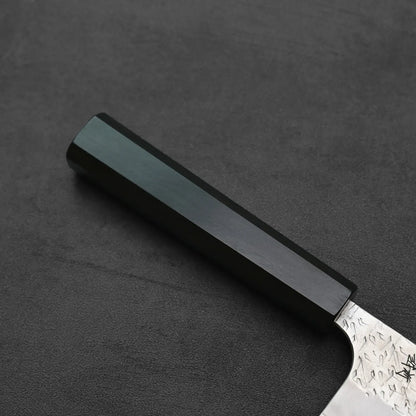 Close-up of gyuto featuring a black hex handle and textured blade.