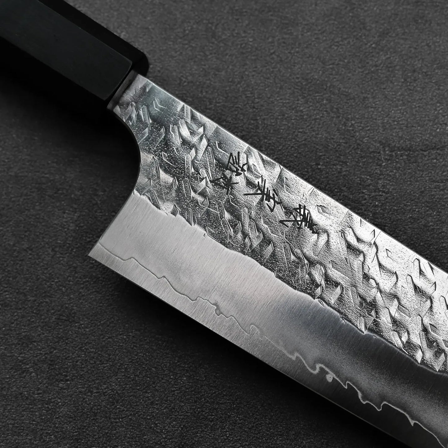 Kiritsuke gyuto with a textured blade and engraved characters shown in close-up detail.