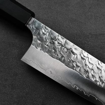 Kiritsuke gyuto with a textured blade and engraved characters shown in close-up detail.