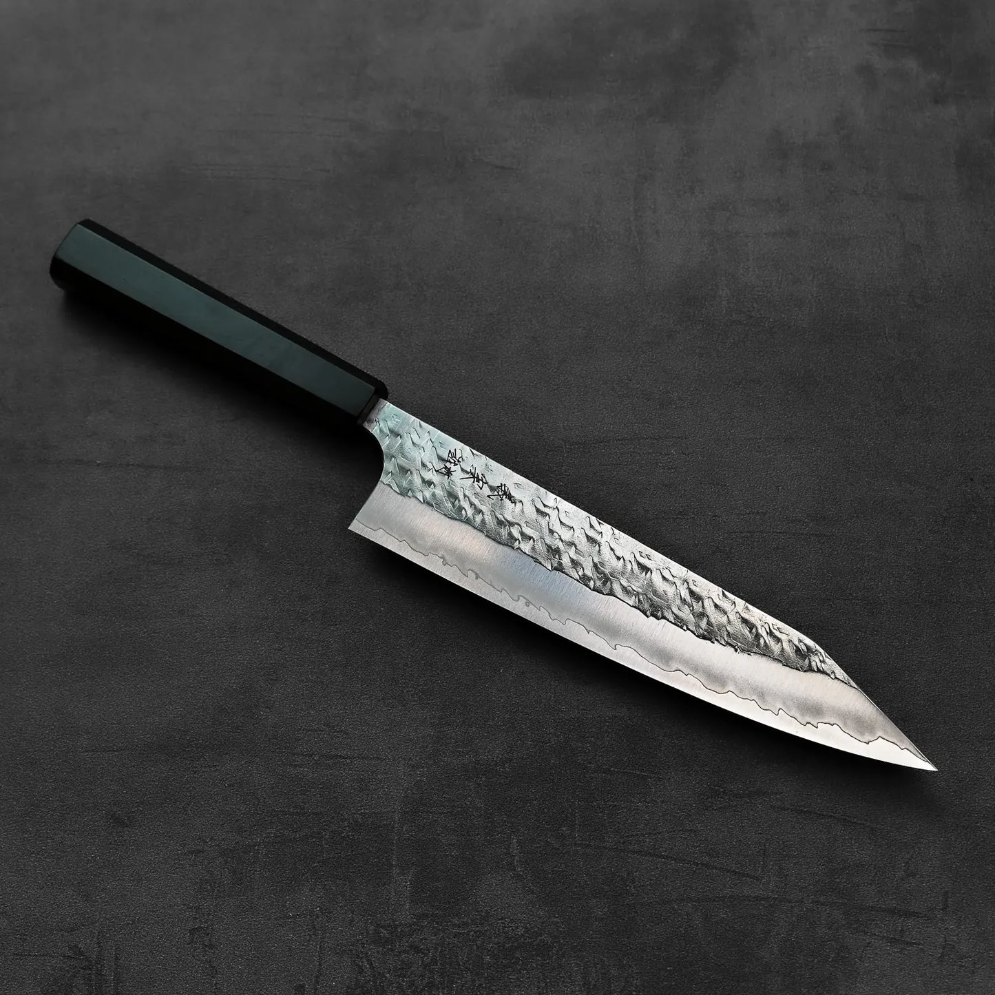 A kiritsuke gyuto with a dark handle and textured blade is displayed, highlighting its features.