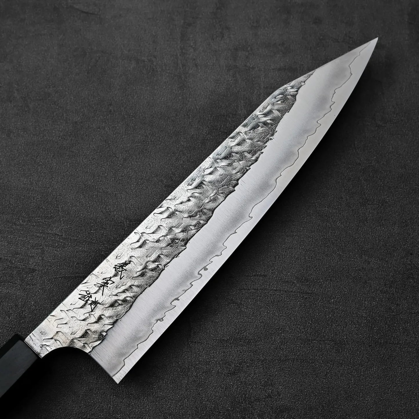 Kiritsuke gyuto with a hammered blade, shown in close-up to highlight its detailed texture.