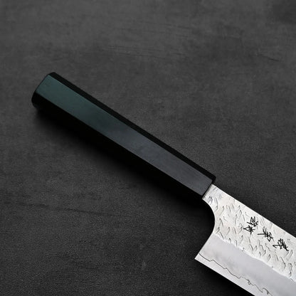 Kiritsuke gyuto featuring a dark handle and a textured blade viewed in close-up.