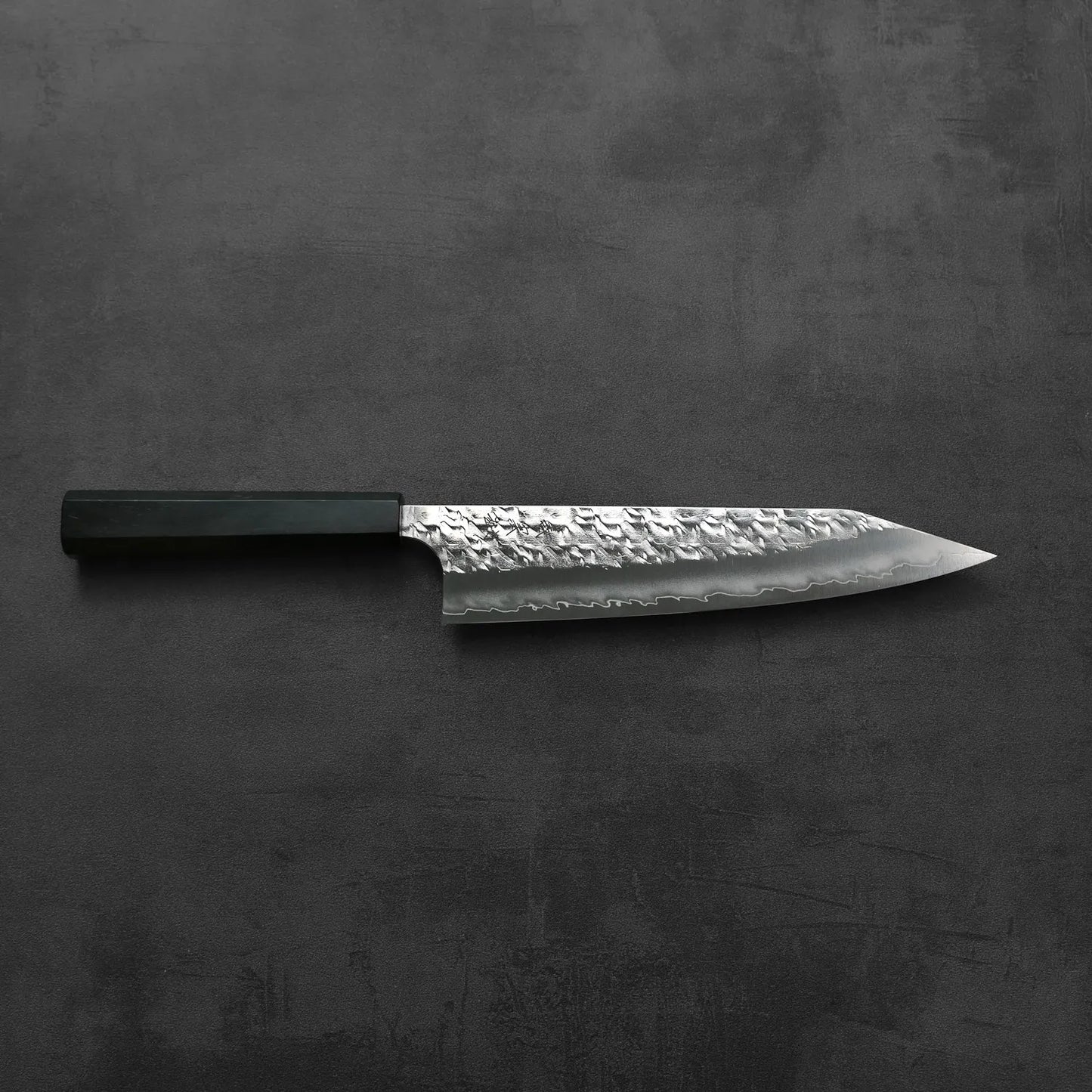 Kiritsuke gyuto with a hammered SG2 blade, black handle, hand-forged in Japan.