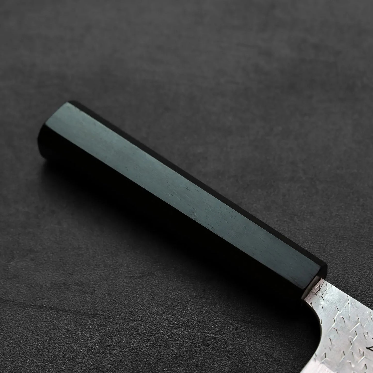 Nakiri with a black handle and visible blade edge, shown in close-up with no background details.