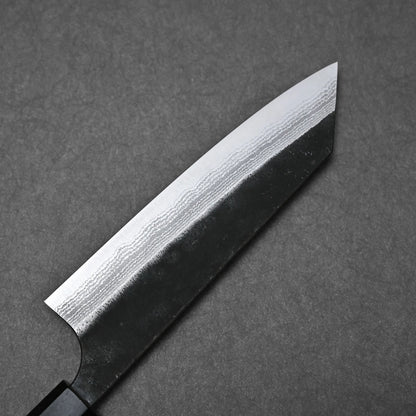 A Yoshimi Kato kurouchi damascus AS bunka 170mm knife with a dark handle and patterned Aogami Super steel blade is shown close-up on a gray textured surface.