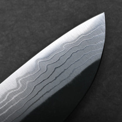 Close-up of the blade of a kurouchi damascus santoku knife showing a wavy, layered pattern typical of Damascus steel, set against a dark background.