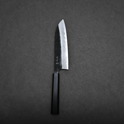 A Kato santoku knife with a patterned damascus blade and a dark handle lies on a flat, dark gray surface.