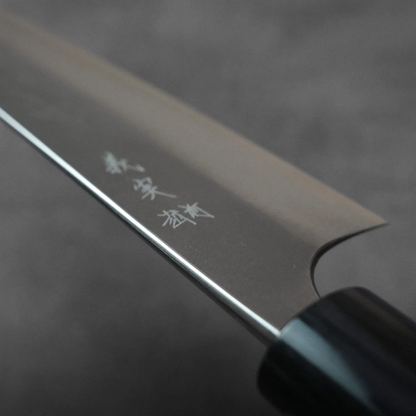 Close-up of a gyuto with Japanese characters engraved near the handle.