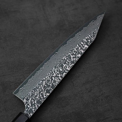 Close-up of a kiritsuke gyuto showing layered pattern and metal detailing on the blade, handle partially visible.