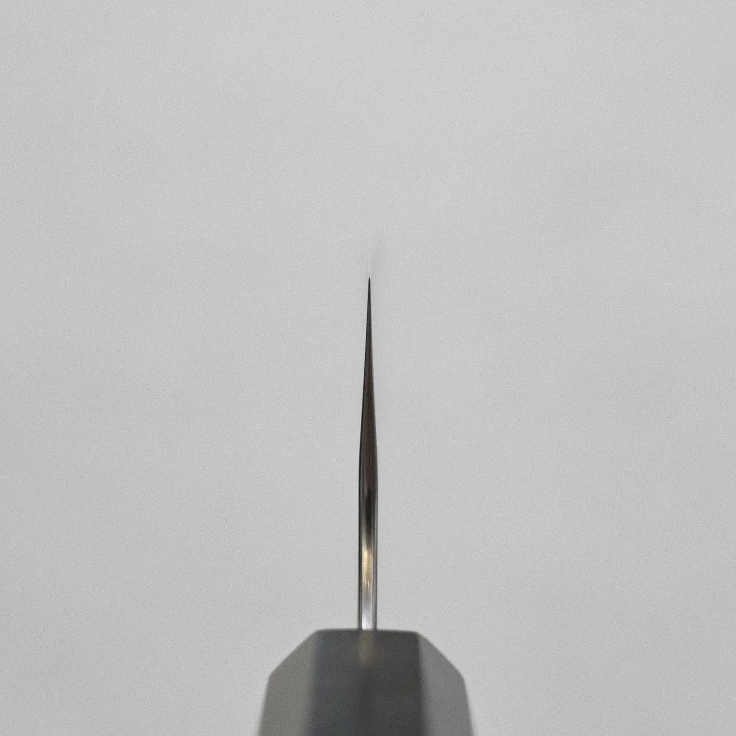 Close-up of a kiritsuke gyuto tip with layered damascus pattern, highlighting the 210mm blade details.