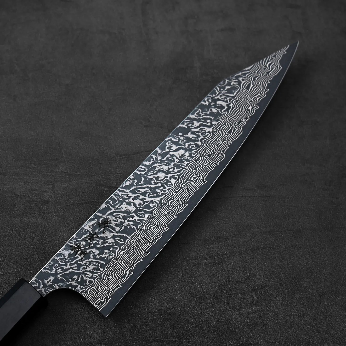 Kiritsuke gyuto with a close-up of its detailed wavy blade pattern visible along the metal.