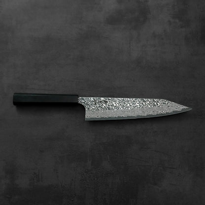 Kiritsuke gyuto with a black handle, blade angled for display, showing detailed damascus pattern.