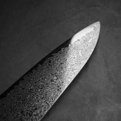 Close up view of the blade of Hatsukokoro ginsan damascus gyuto 210mm. Image focuses on the tip area of the left blade side