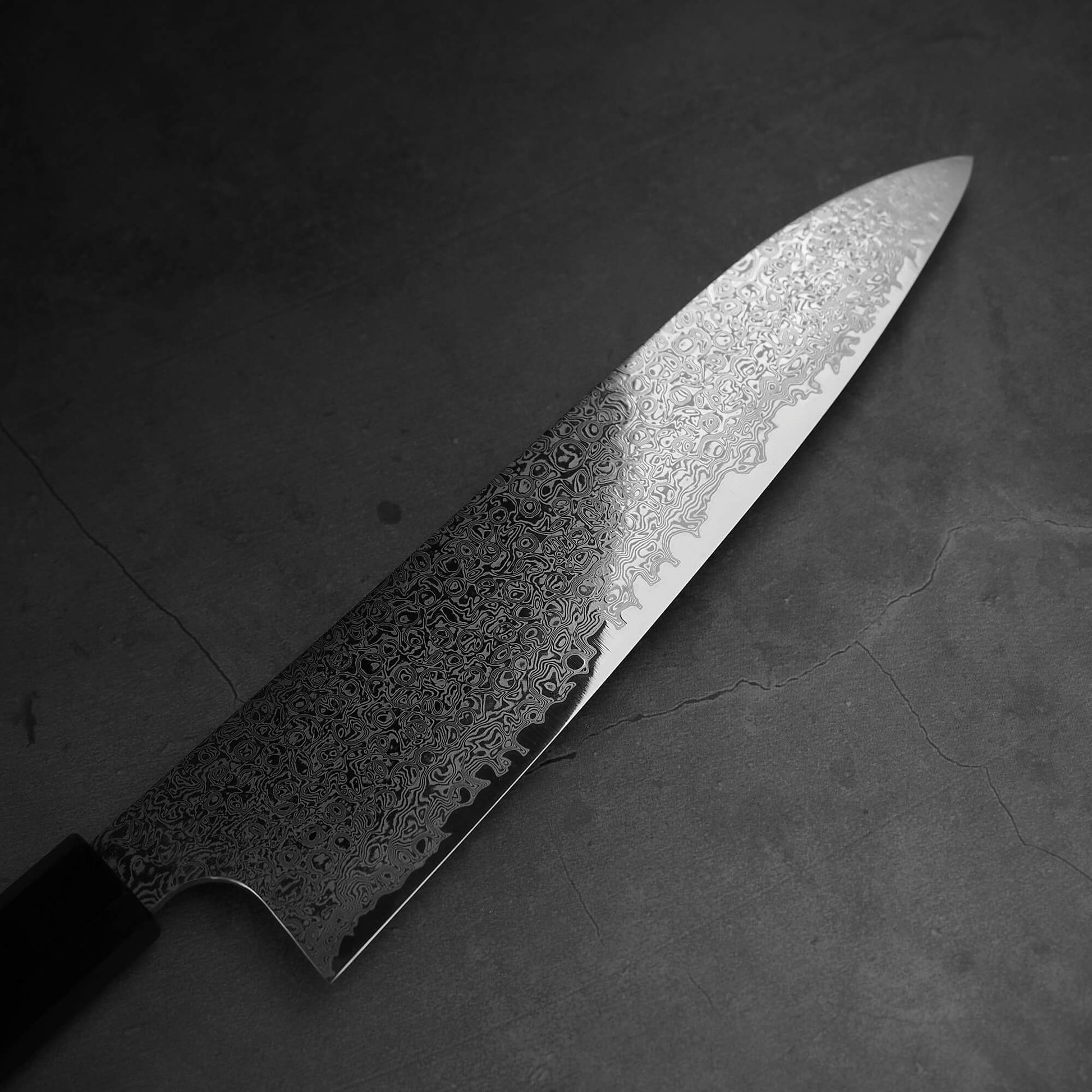 Top view of the blade of Hatsukokoro ginsan damascus gyuto 210mm. Image focuses on the right blade side