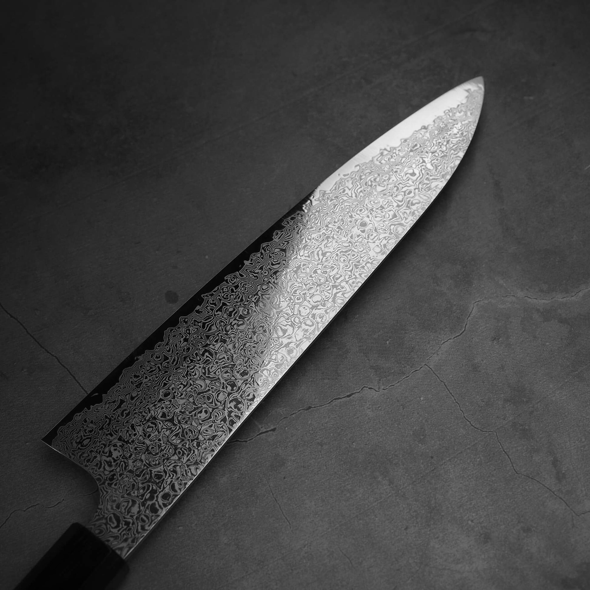 Top view of the blade of Hatsukokoro ginsan damascus gyuto 210mm. Image focuses on the left side of the blade