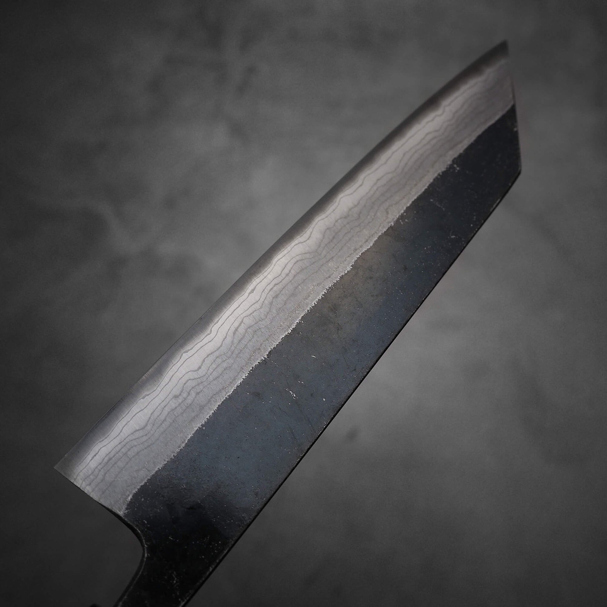 Top view of Hatsukokoro Kumokage kurouchi damascus aogami#2 bunka knife. Image shows the left side of the knife.