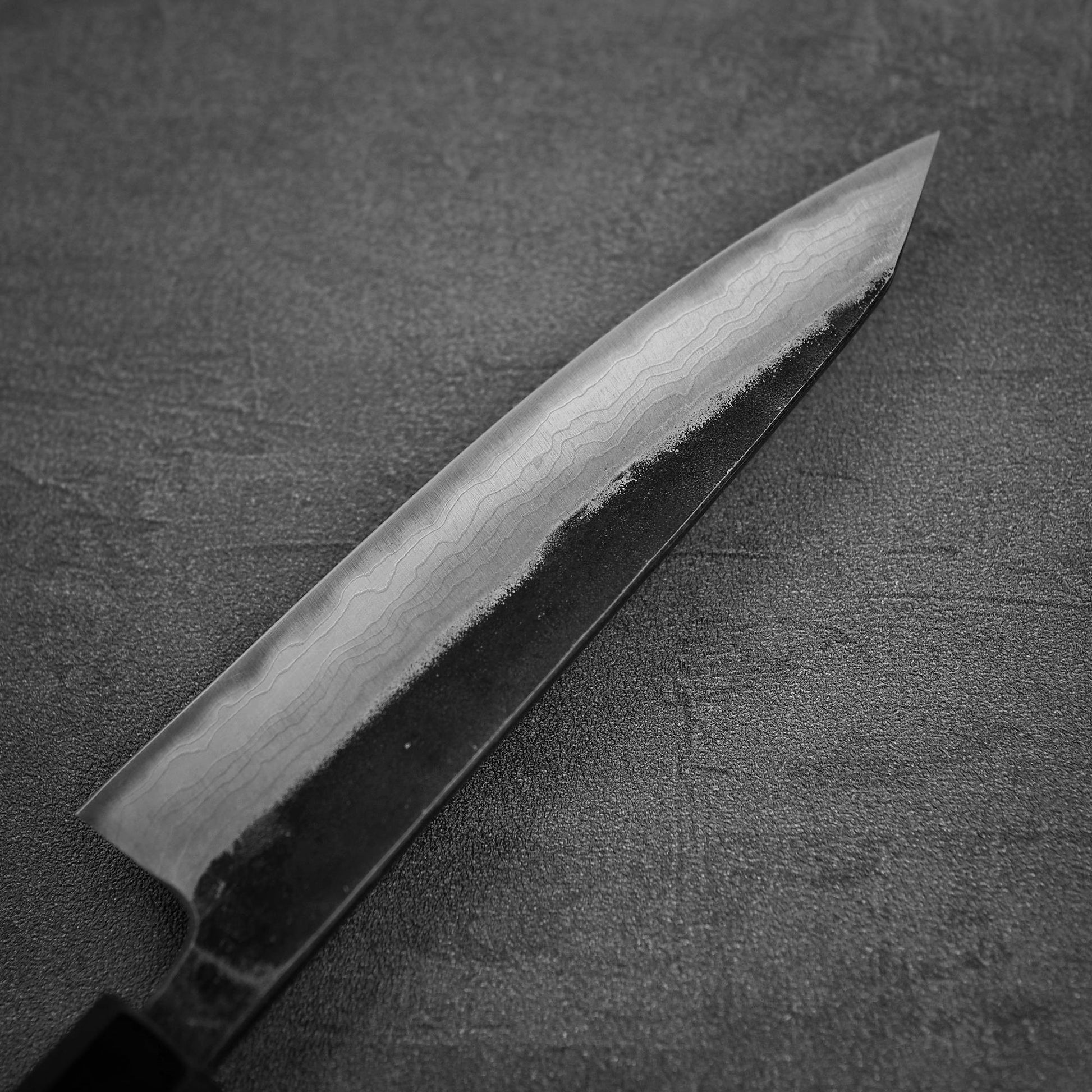 Close up view of the back side of Hatsukokoro Kumokage kurouchi damascus aogami#2 honesuki knife