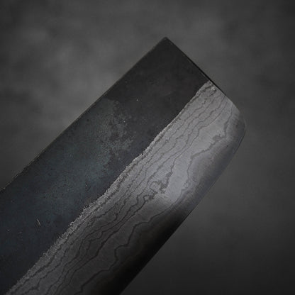 Close up view of Hatsukokoro Kumokage kurouchi damascus aogami#2 nakiri knife. Image focuses around the tip area of the right side of the blade