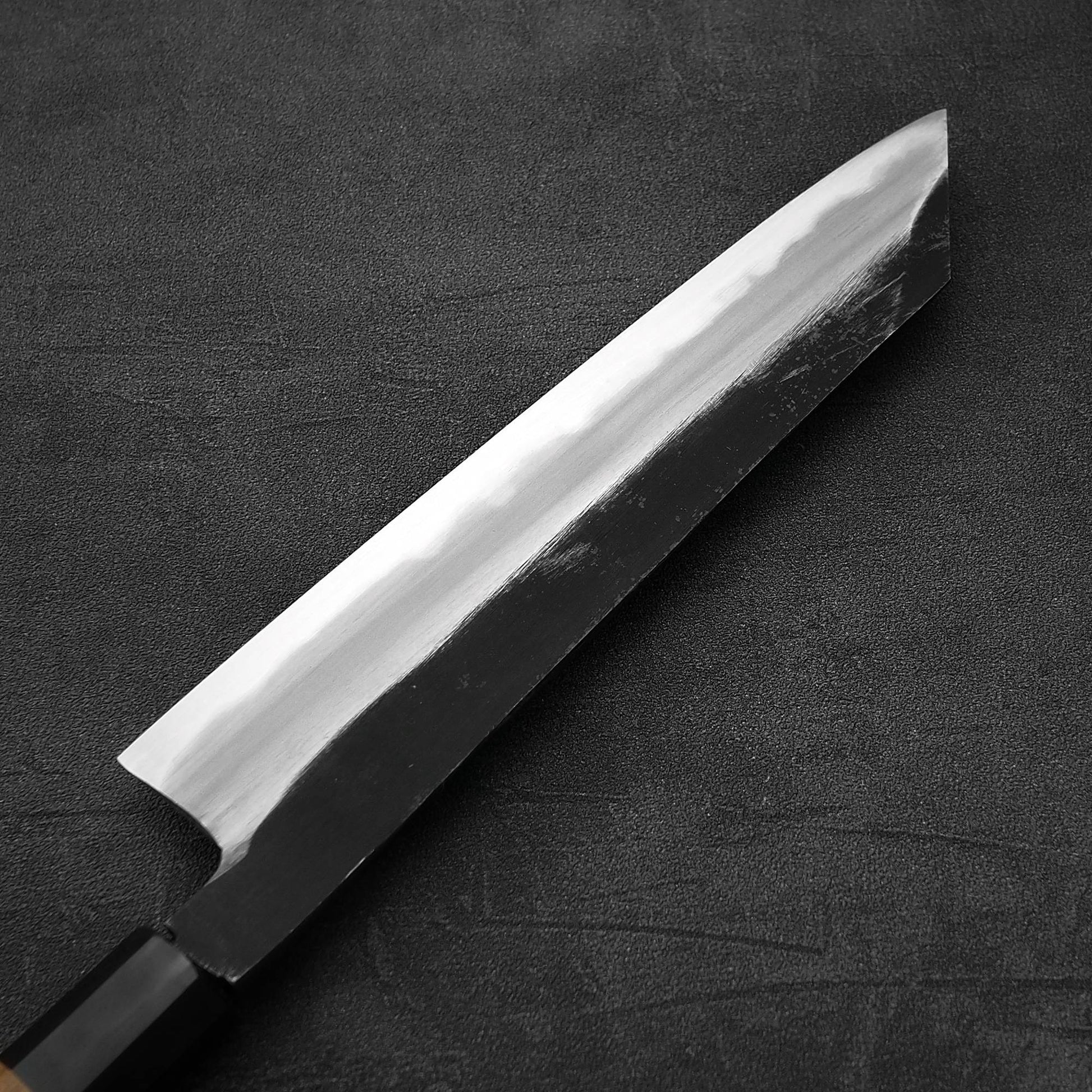 Close up view of the back side of Hatsukokoro Yoake kurouchi aogami#1 kiritsuke gyuto knife