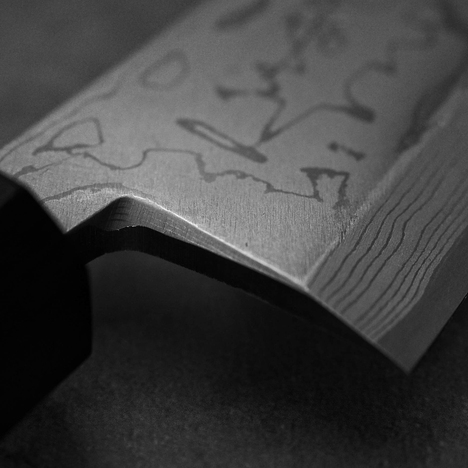 Close up view of Hideo Kitaoka damascus aogami#2 mioroshi deba 210mm. Image focuses on the choil area of the knife.