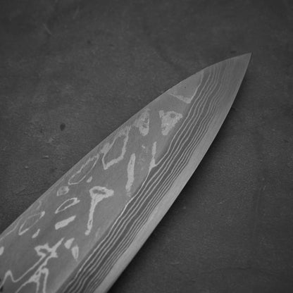 Close up view of Hideo Kitaoka damascus aogami#2 mioroshi deba 210mm. Image focuses on the tip area of the right side of the blade.