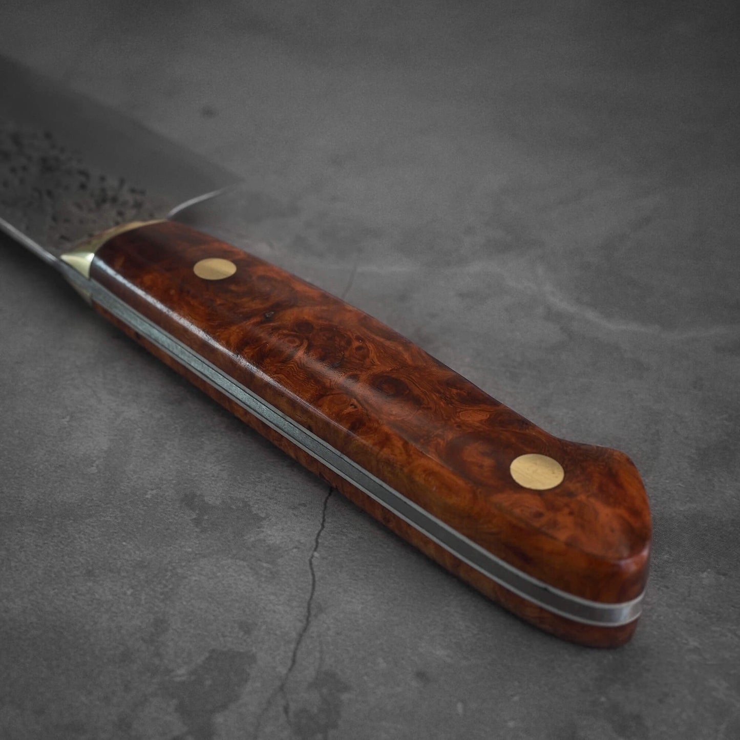 An angled view and close up shot of the handle of a 220mm Kisuke Manaka tsuchime honwarikomi shirogami#2 gyuto knife