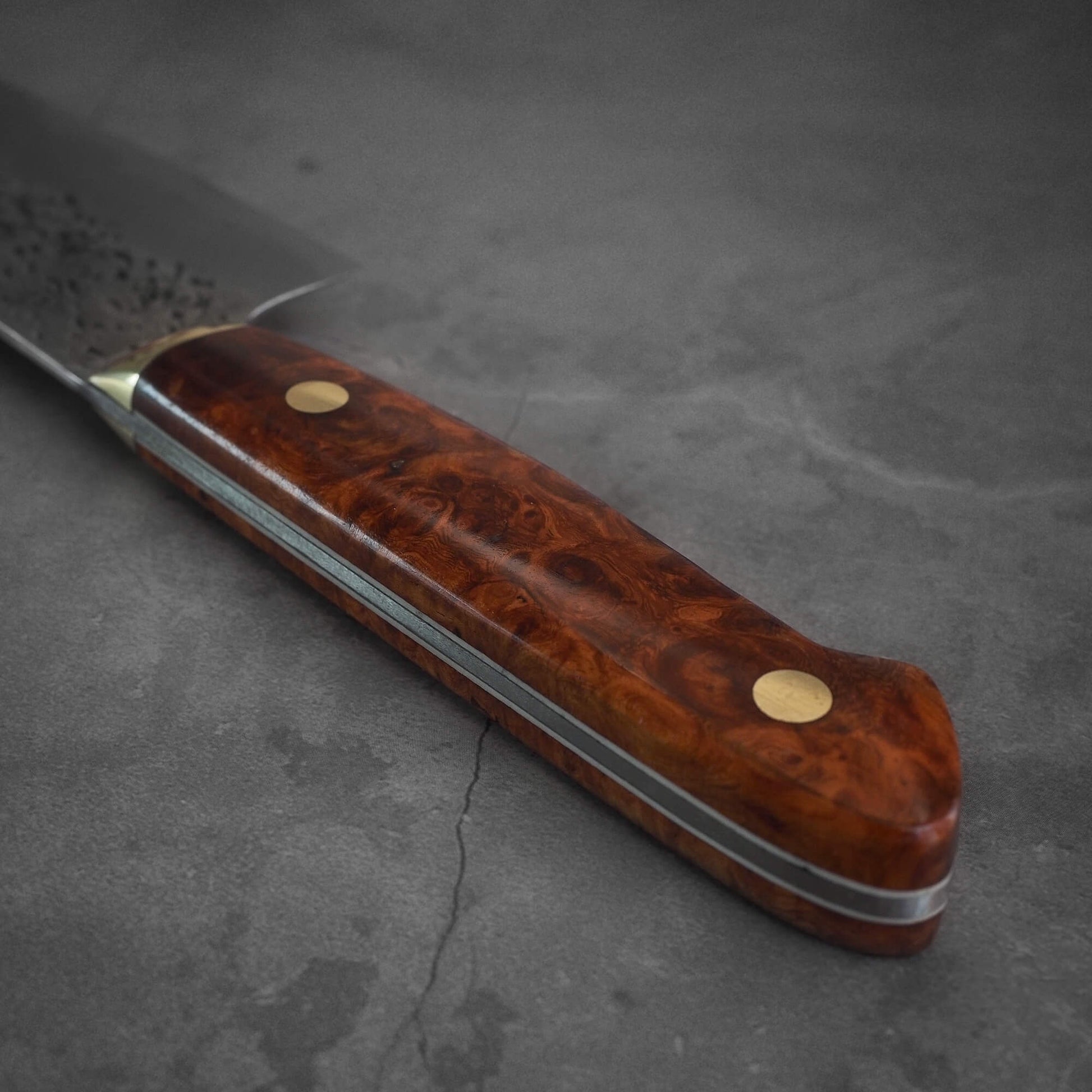 An angled view and close up shot of the handle of a 220mm Kisuke Manaka tsuchime honwarikomi shirogami#2 gyuto knife