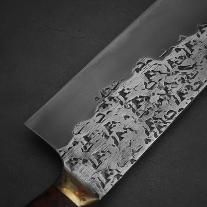 Close up view of 240mm Kisuke Manaka tsuchime honwarikomi shirogami#2 gyuto knife. Image focuses on the left side of the knife around the heel