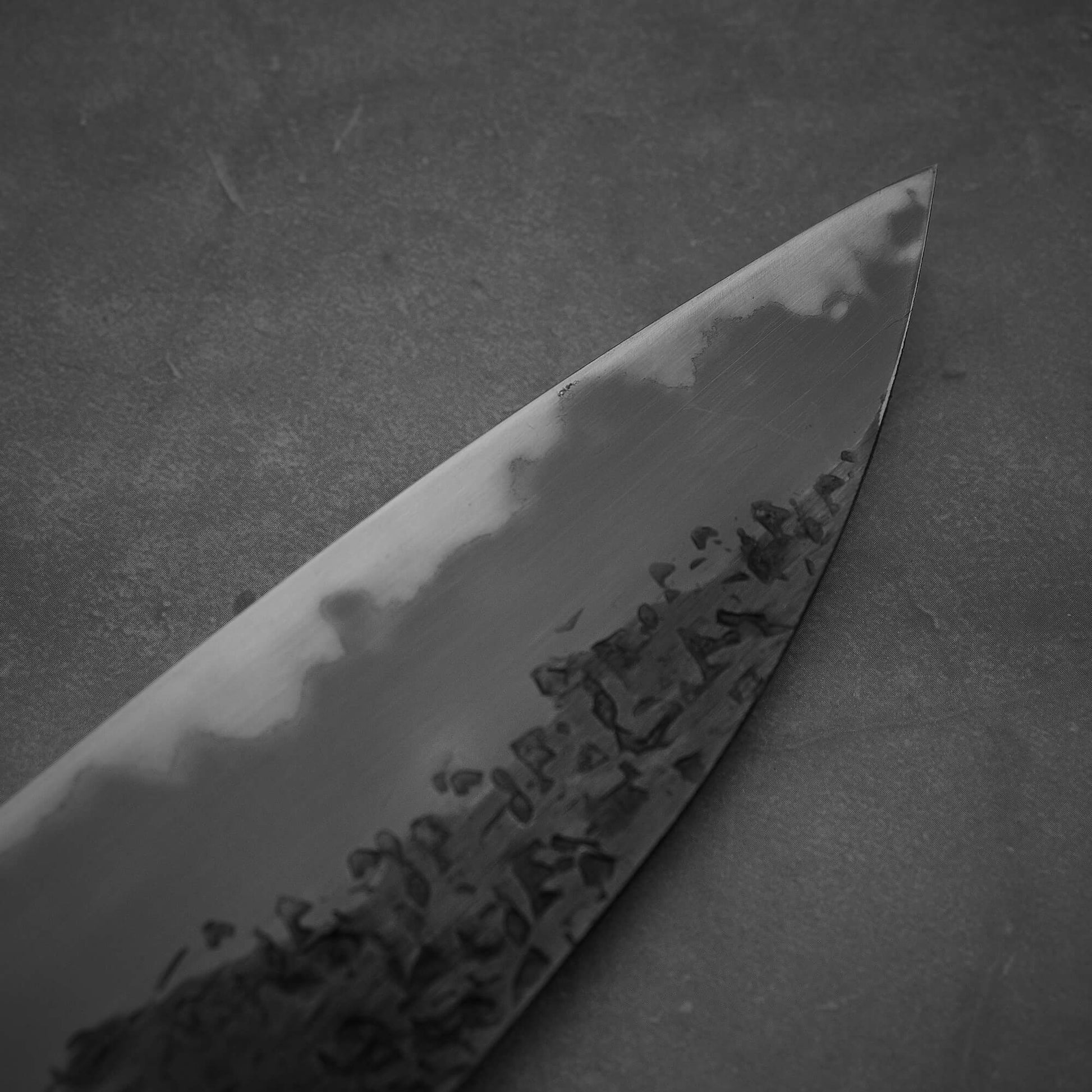 Close up view of the tip area of Kisuke Manaka tsuchime kurouchi white#2 gyuto 240mm western. Image shows the left side of the blade.