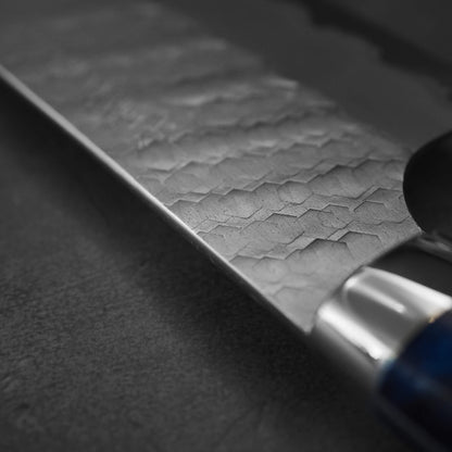 Close up view of 210mm Nigara tsuchime SG2 gyuto knife with blue handle showing the spine
