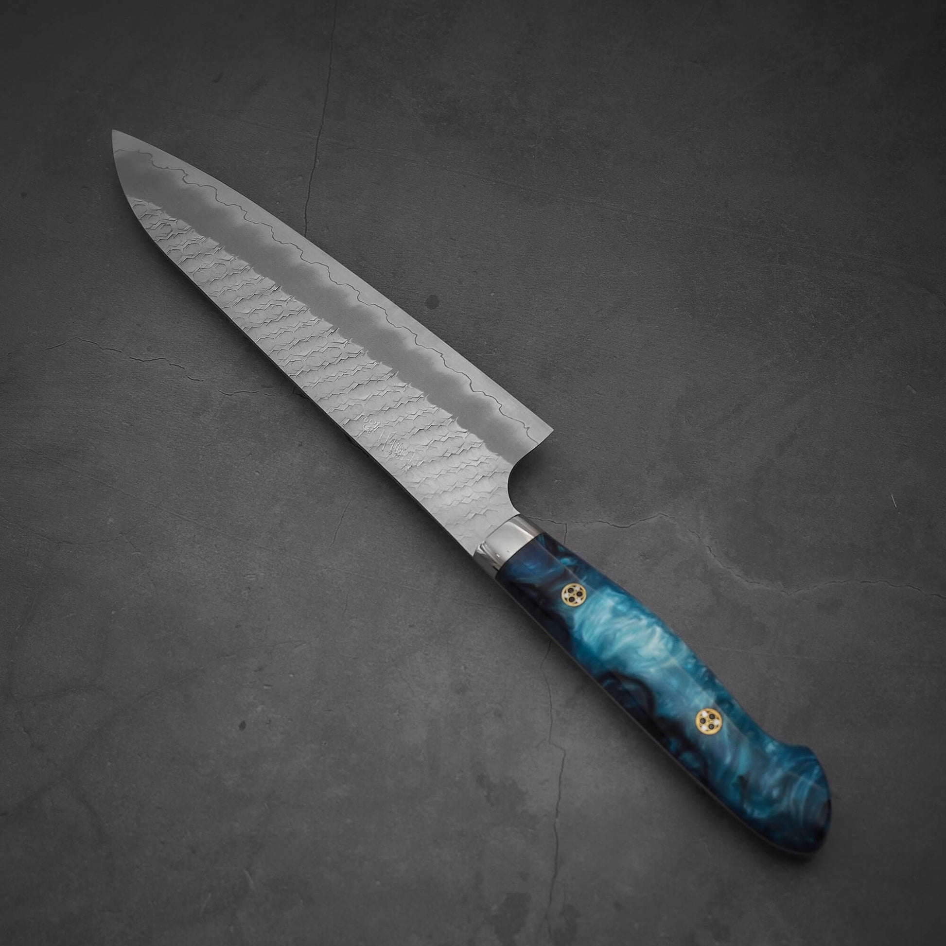 Top view of 210mm Nigara tsuchime SG2 gyuto knife with blue handle in diagonal position handle at the bottom right