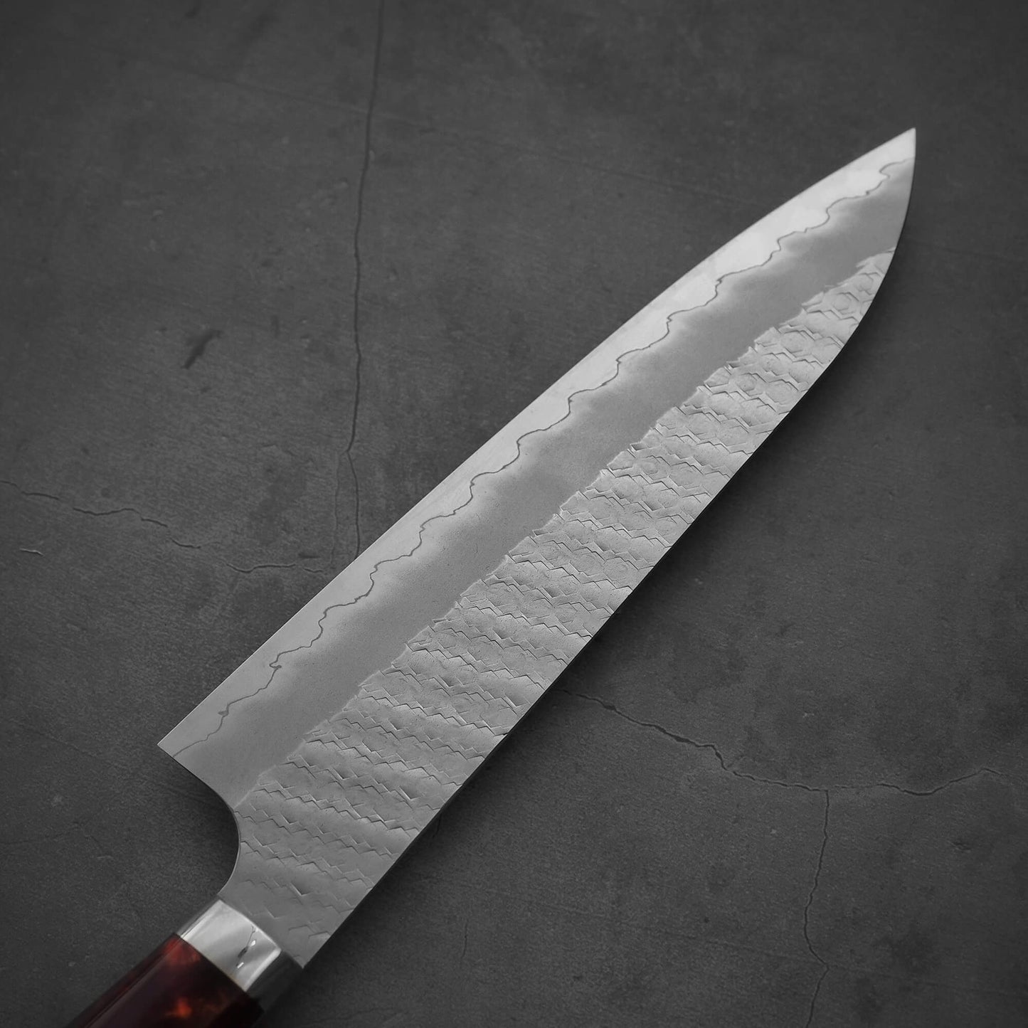 Front view of the blade of 210mm Nigara tsuchime SG2 gyuto knife with red handle on the other side