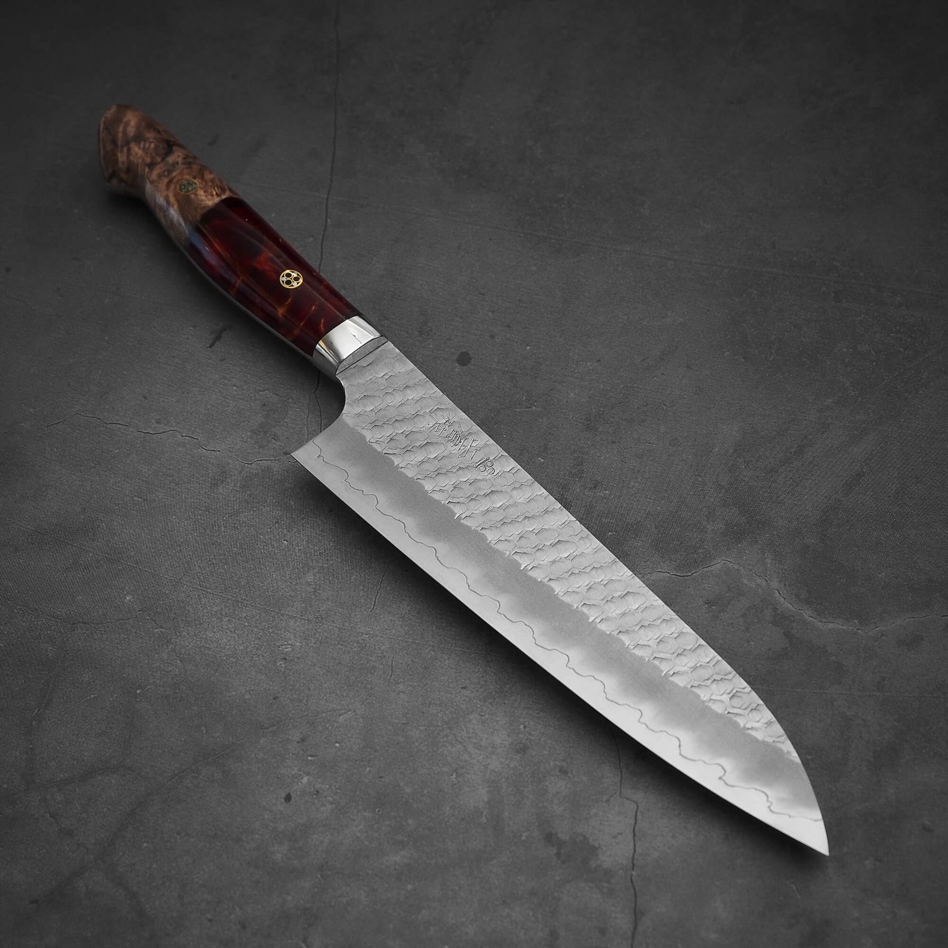 Top view of 210mm Nigara tsuchime SG2 gyuto knife with red handle in diagonal position where tip is pointing on bottom right