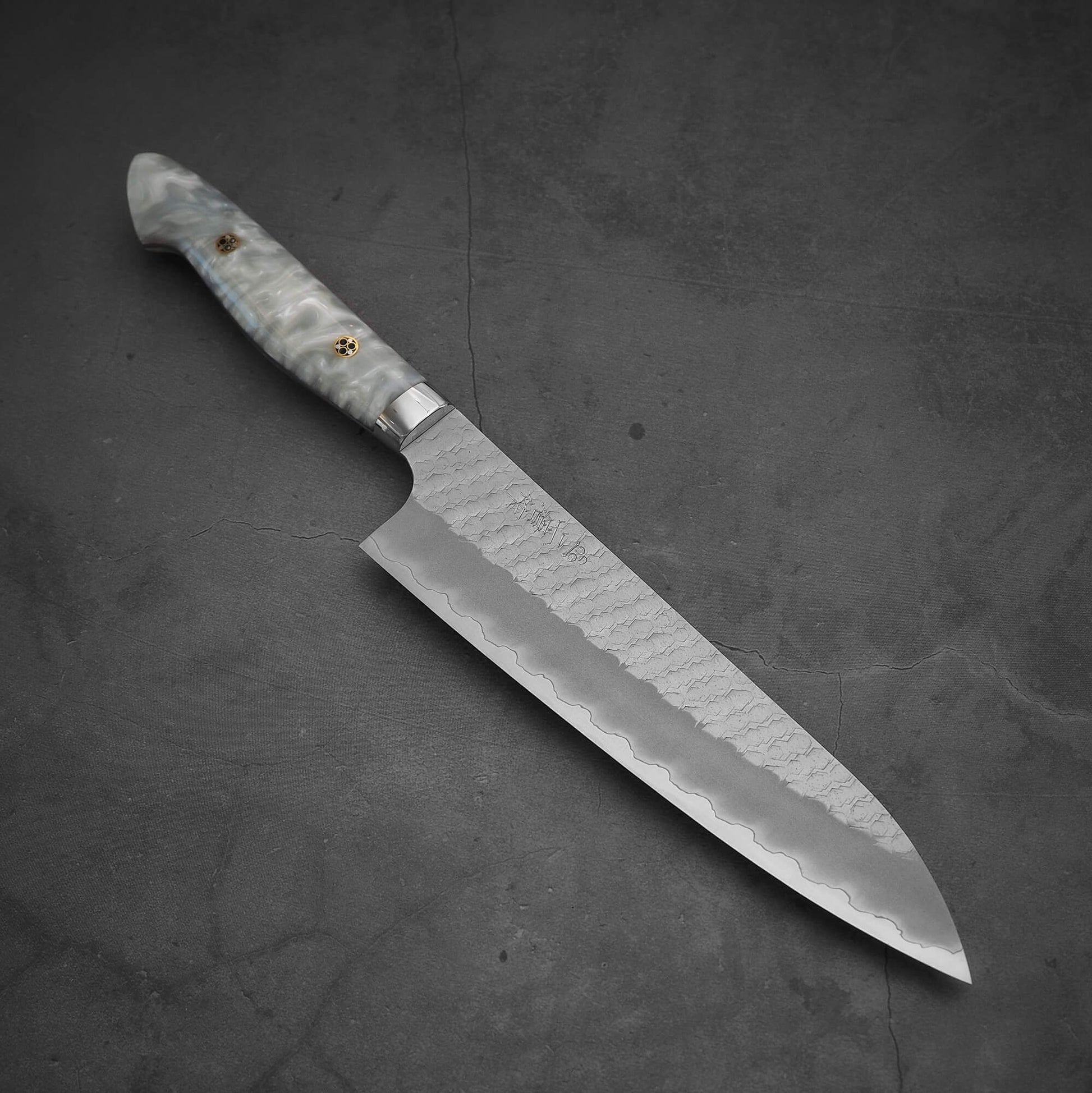 Top view of 210mm Nigara tsuchime SG2 gyuto knife with pearl handle resin in diagonal position where tip is pointing on bottom right