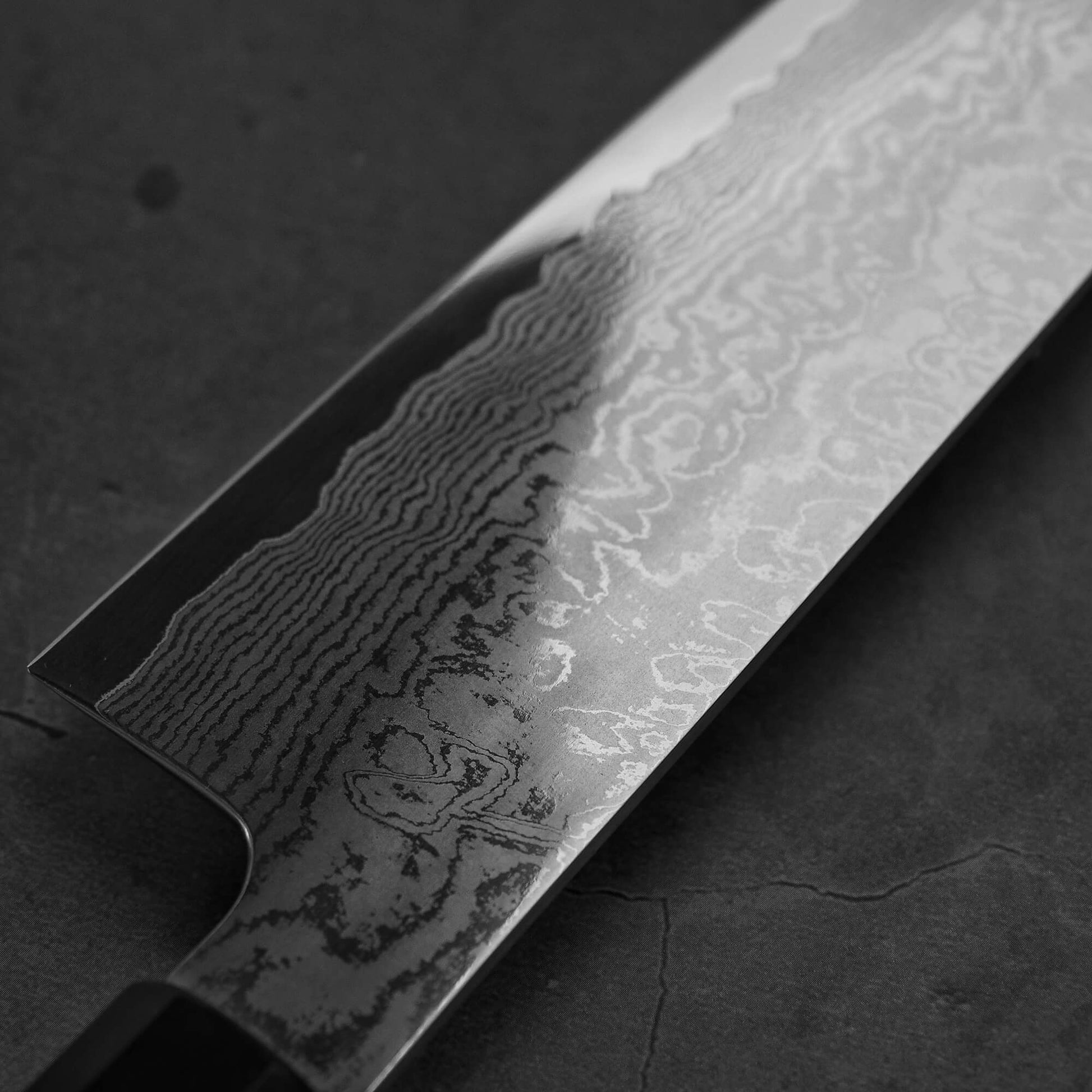 Close up view of the Sukenari damascus XEOS gyuto . Image focuses on the heel area of the left side of the blade
