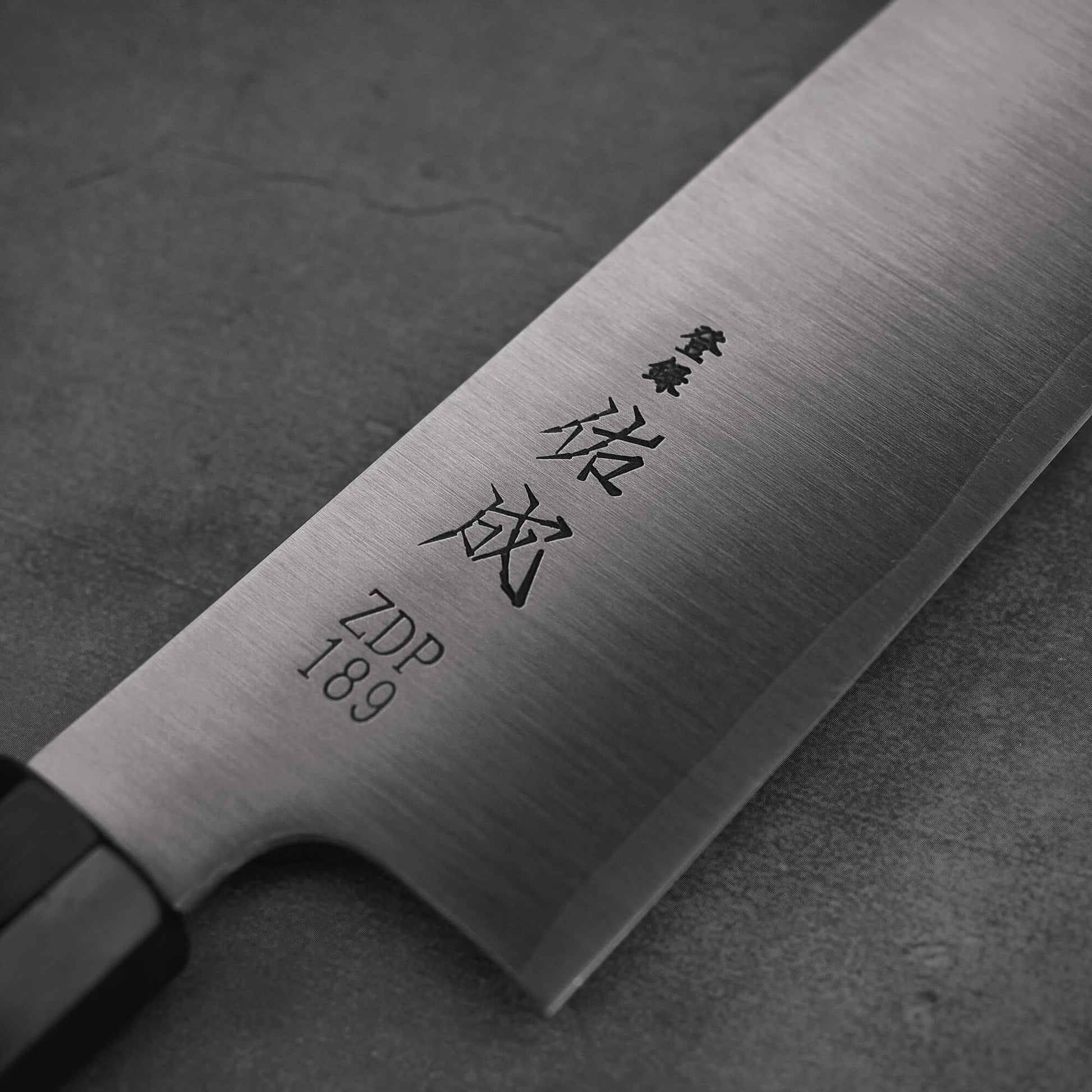 Close up view of 210mm Sukenari ZDP189 gyuto knife focusing on the kanji