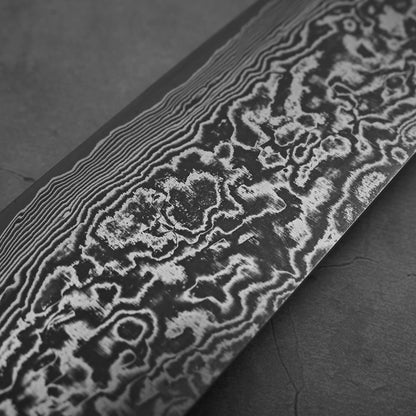 Another close up view of Takeshi Saji black damascus SG2 nakiri ironwood. Image focuses on the left side of the blade