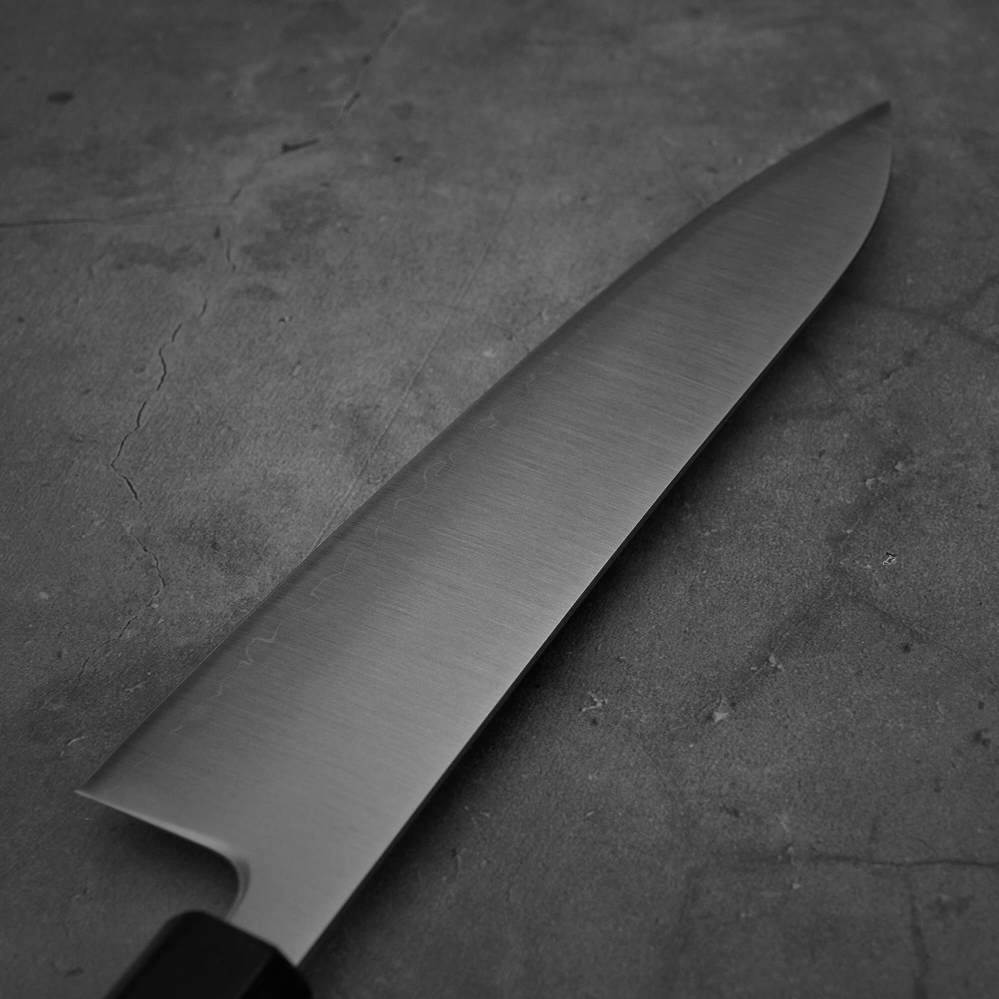 Close up view of the backside of Yoshihiro migaki aogami super gyuto. This Japanese chef's knife has an octagonal rosewood handle.
