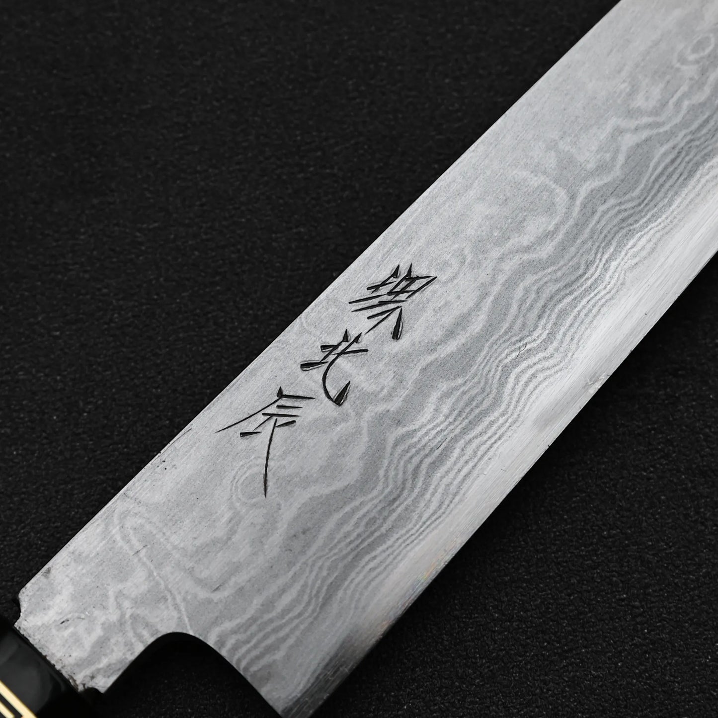 Close up view of the kanji of Yoshikazu Ikeda aogami#1 damascus slim gyuto knife