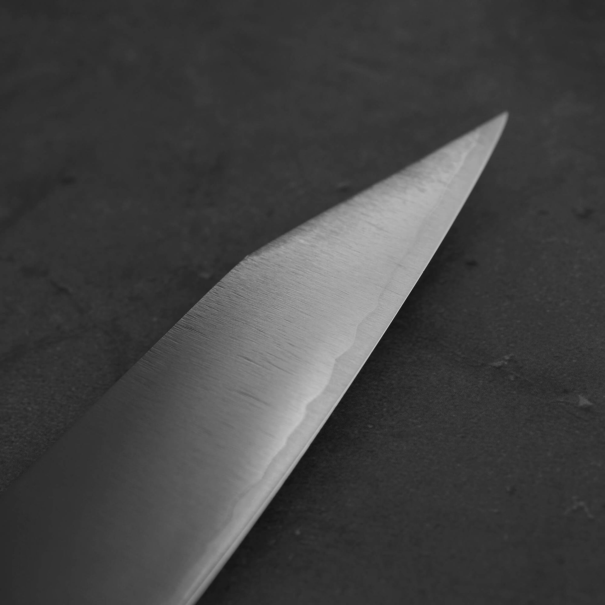 Close up view of Yu Kurosaki HAP40 Gekko kiritsuke sujihiki 270mm. Image focuses on the tip of the right blade side.