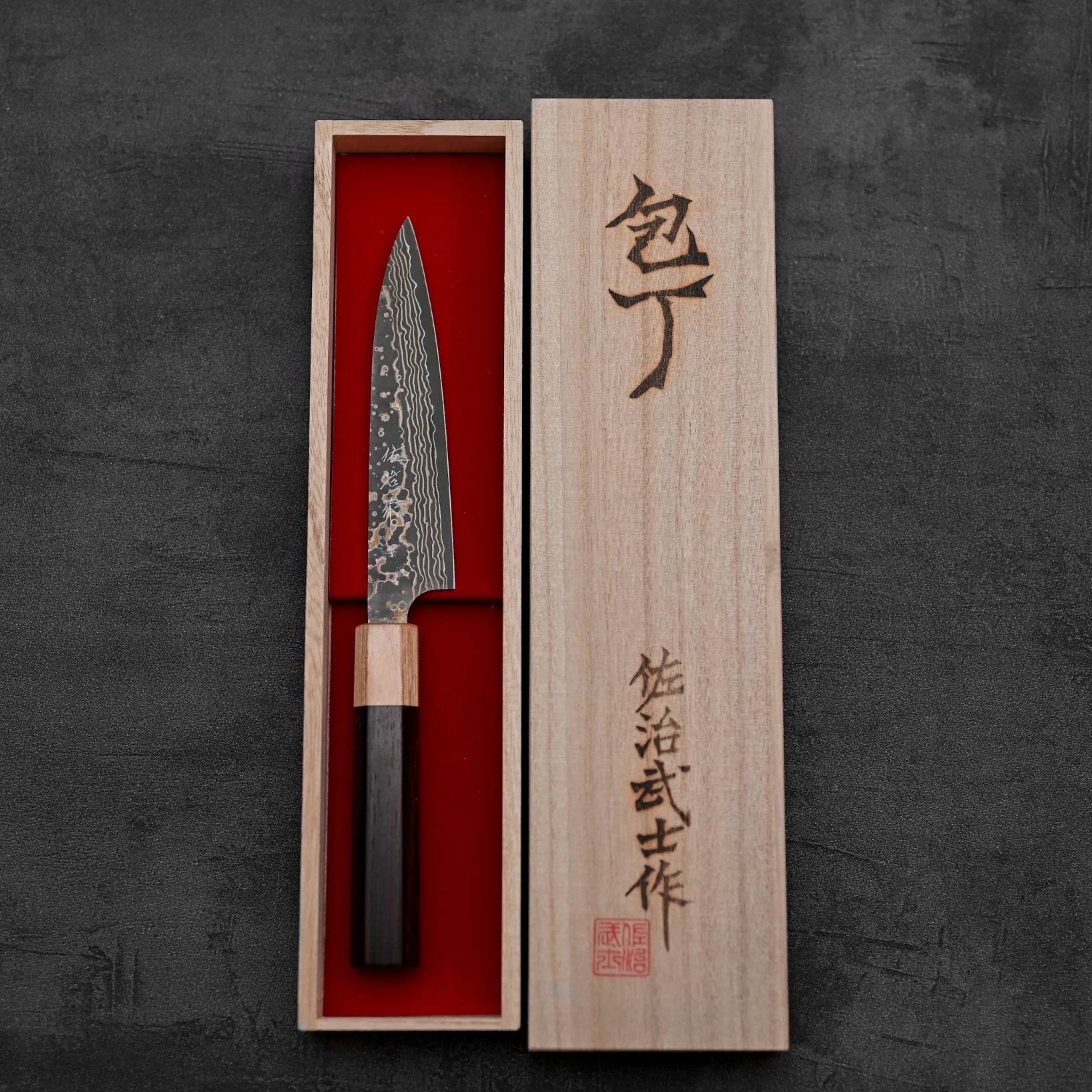 Top down view of Takeshi Saji VG10 Gold damascus petty knife inside its kiri box