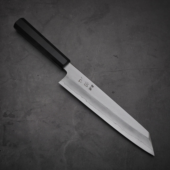 Top view of Hatsukokoro Nakagawa ginsan kiritsuke gyuto knife where pointed tip is facing towards lower right