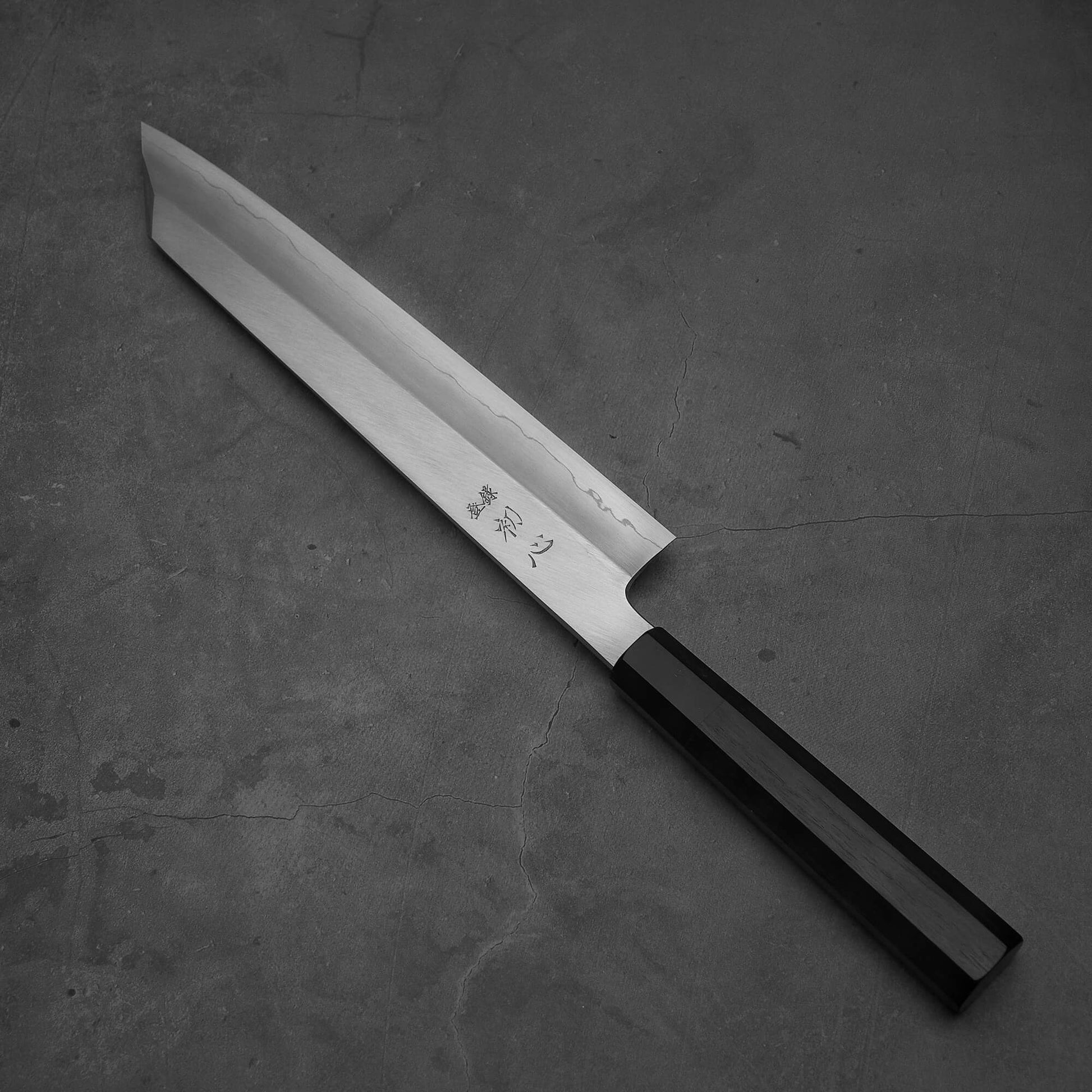 Top view of Hatsukokoro Nakagawa ginsan kiritsuke gyuto knife where pointed tip is facing towards upper left