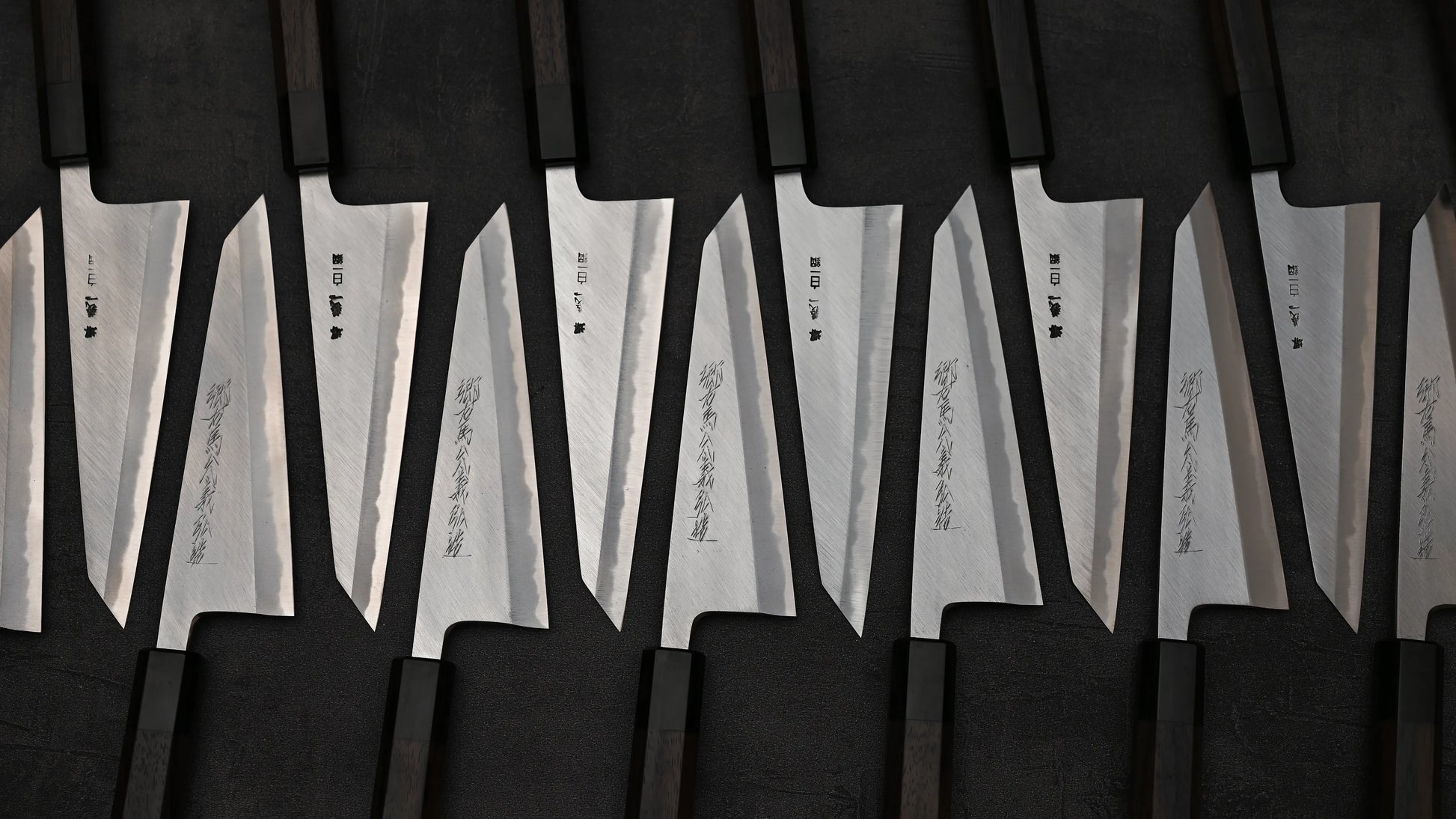 An array of Yoshikazu Tanaka shirogami#1 double bevel honesuki knives in alternating positions