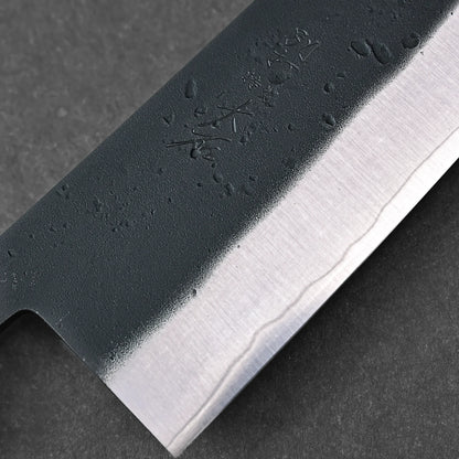 Close-up of the Ohishi kurouchi SLD gyuto 210mm knife blade by Ohishi, featuring a polished edge, textured upper section with engraved Japanese characters and water droplets, showcasing its craftsmanship.
