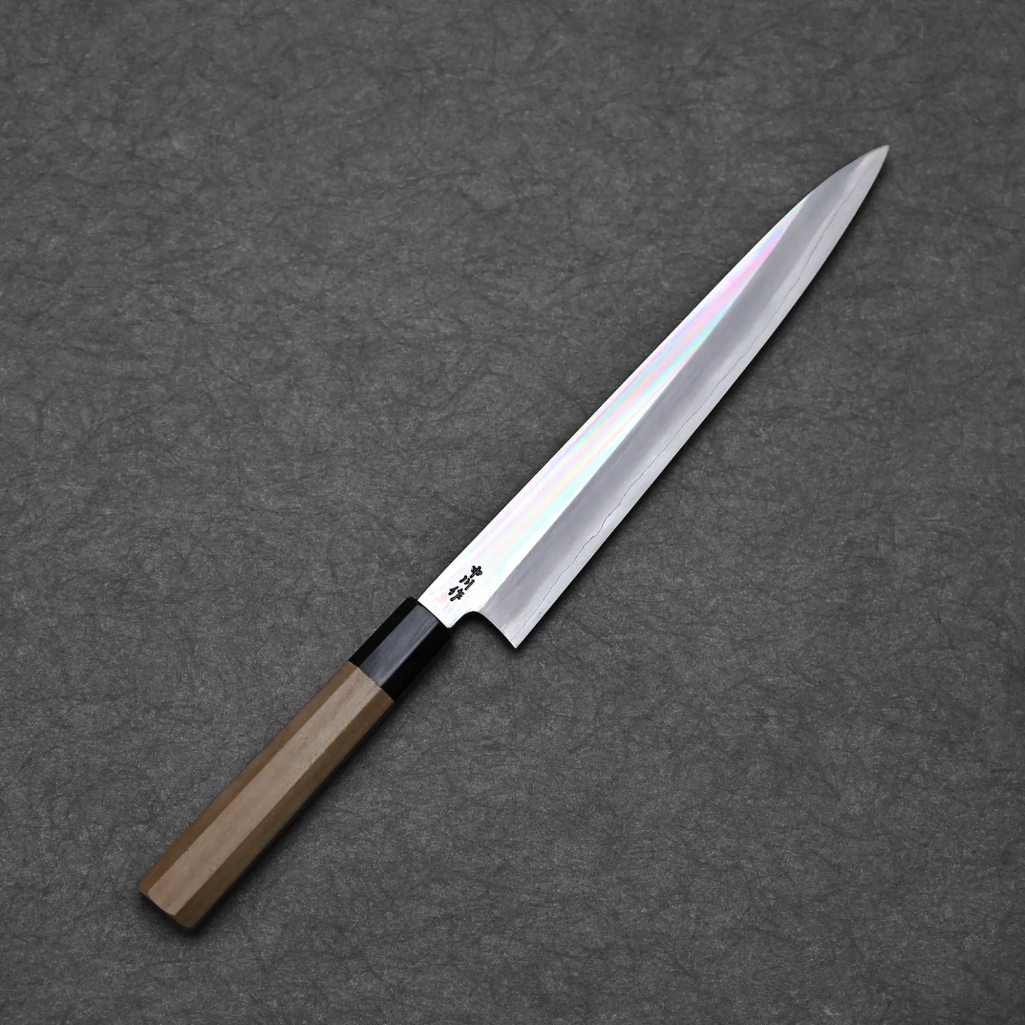 Full blade profile of Nakagawa ginsan 210mm petty knife with mirror polished hira and octagonal magnolia handle against dark background