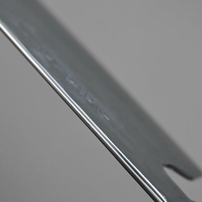 Close-up of the Teruyasu Fujiwara Maboroshi shirogami#1 nakiri 165mm, showcasing its polished spine and choil, smooth reflective edge, and a small notch, set against a plain gray background.