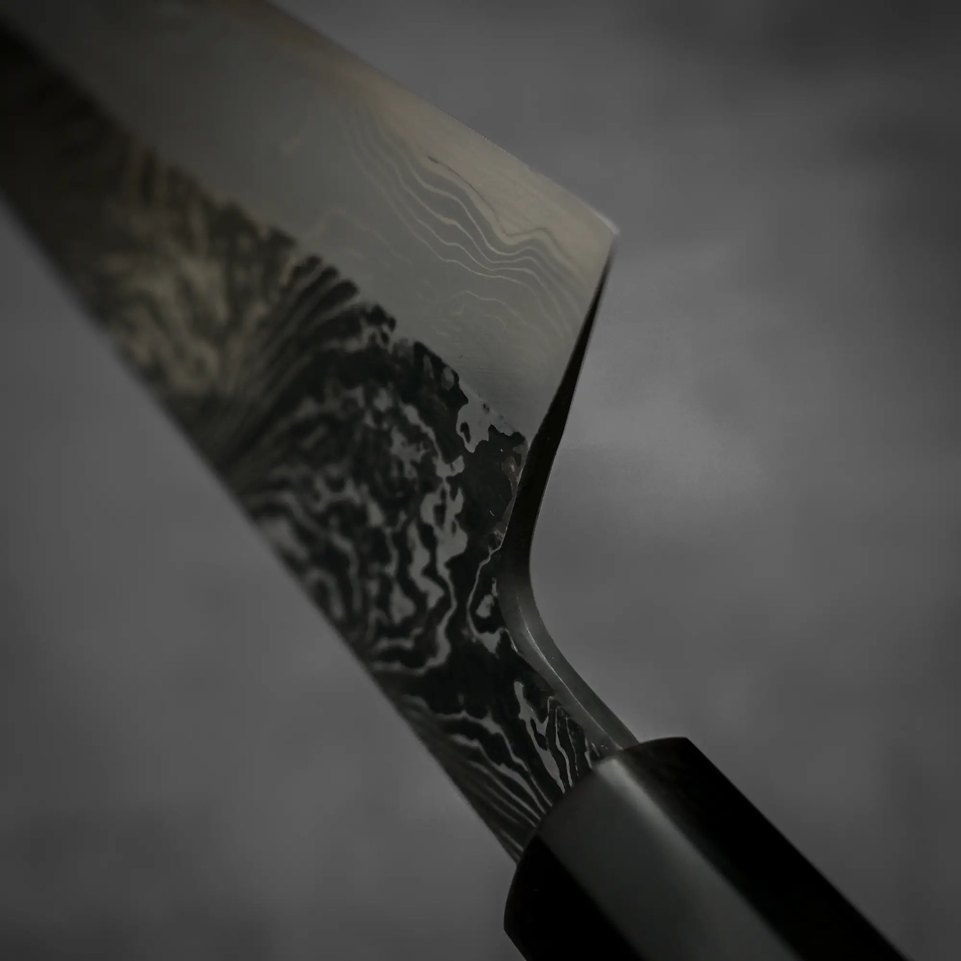 Macro shot of the choil section of Yoshihide Masuda shirogami#2 kurouchi damascus tall gyuto knife